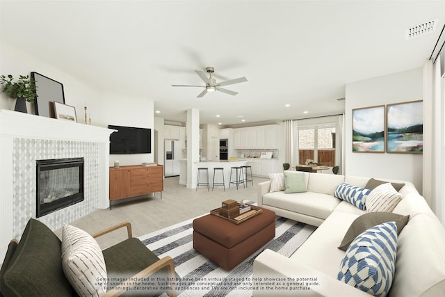 living area with a ceiling fan, recessed lighting, visible vents, and a tiled fireplace