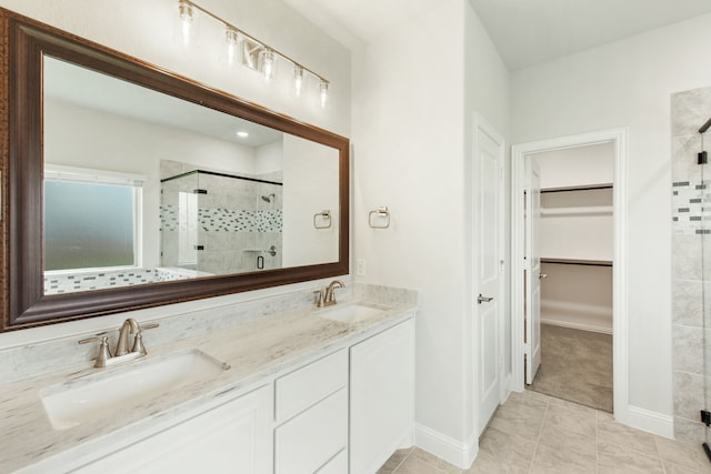 bathroom with a stall shower, a walk in closet, a sink, and double vanity