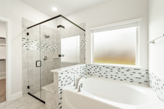 full bathroom with a spacious closet, a stall shower, tile patterned flooring, and a bath