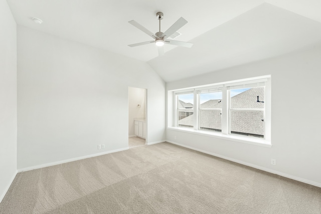 empty room featuring a ceiling fan, lofted ceiling, light colored carpet, and baseboards