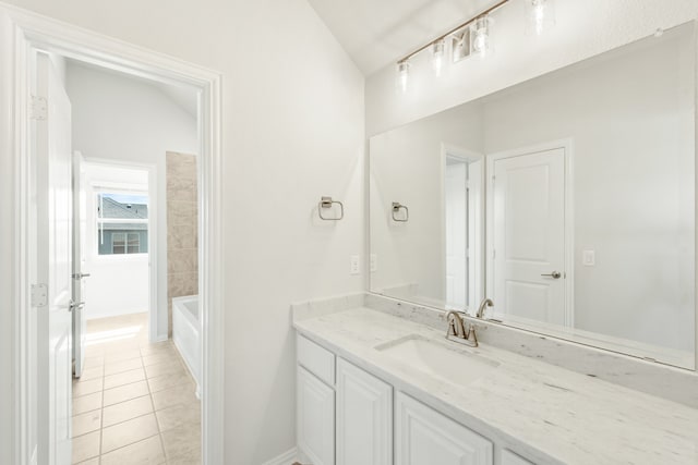 bathroom with a bathing tub, tile patterned flooring, vaulted ceiling, and vanity