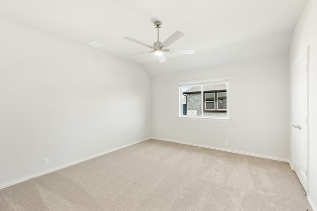 empty room featuring light carpet, ceiling fan, baseboards, and lofted ceiling