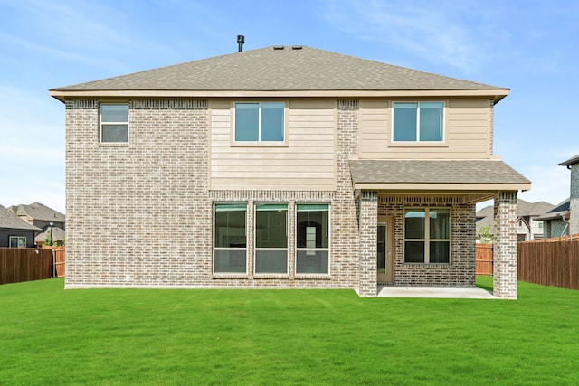 rear view of house with a fenced backyard, brick siding, a shingled roof, a lawn, and a patio area