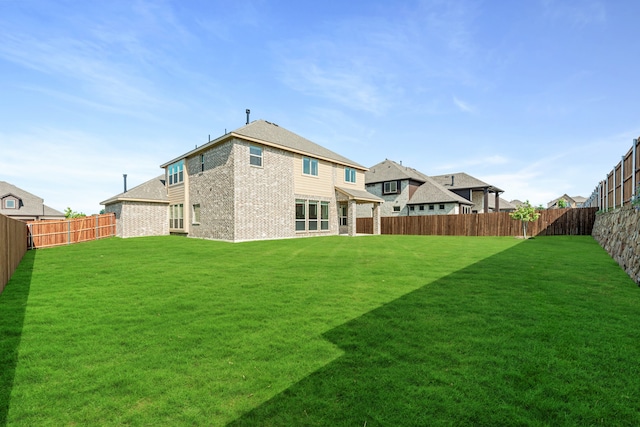 back of property with brick siding, a lawn, and a fenced backyard