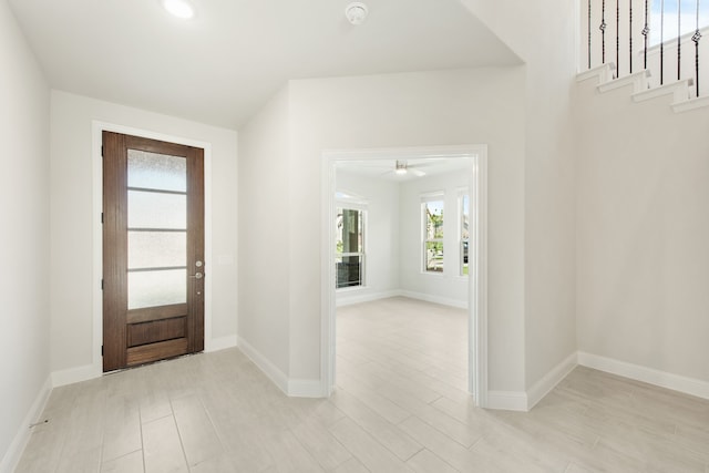 entrance foyer featuring light wood-style flooring, baseboards, and stairs