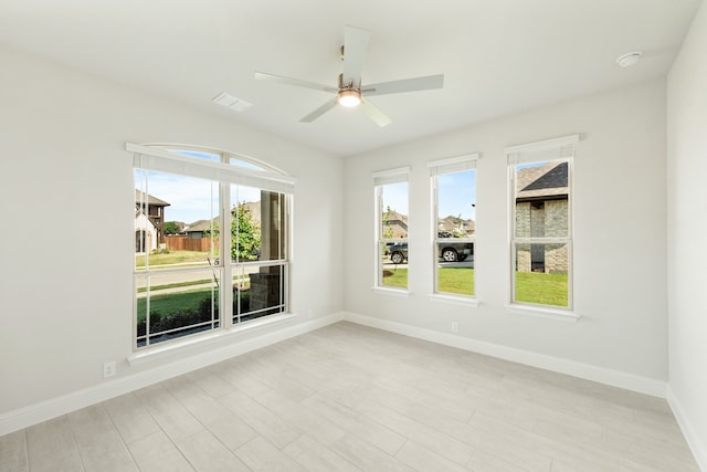 unfurnished room with a ceiling fan, light wood-style floors, visible vents, and baseboards