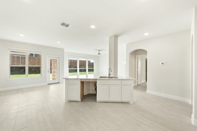 kitchen with arched walkways, recessed lighting, a sink, visible vents, and open floor plan