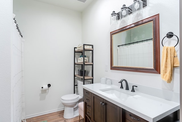 bathroom with toilet, vanity, and hardwood / wood-style flooring