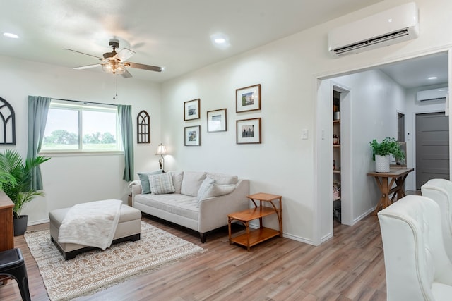 living room featuring an AC wall unit, ceiling fan, and light wood-type flooring