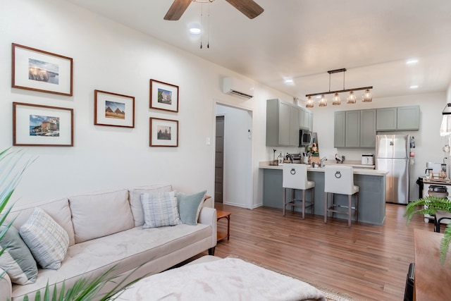 living room with wood-type flooring, a wall unit AC, ceiling fan, and rail lighting