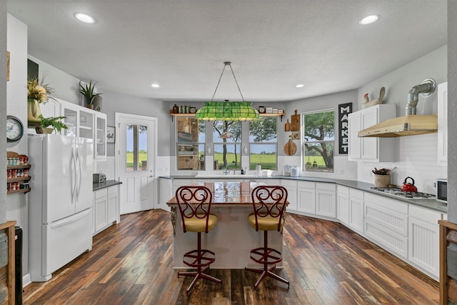 kitchen featuring a center island, dark wood-type flooring, white cabinetry, backsplash, and stainless steel appliances