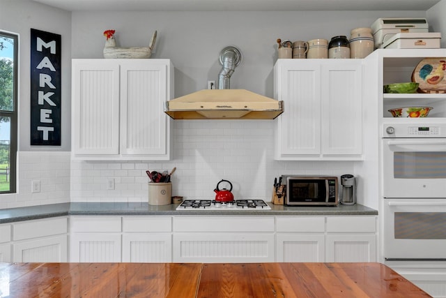 kitchen with backsplash, gas stovetop, white cabinetry, and white double oven