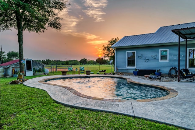 pool at dusk with a patio and a yard