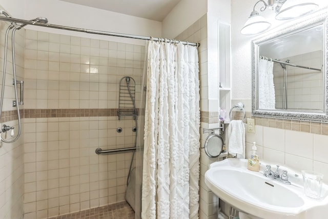 bathroom featuring walk in shower, tile walls, and sink