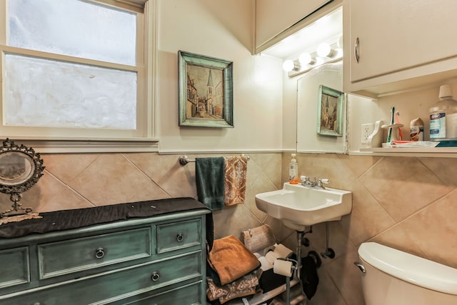 bathroom featuring sink, tile walls, and toilet