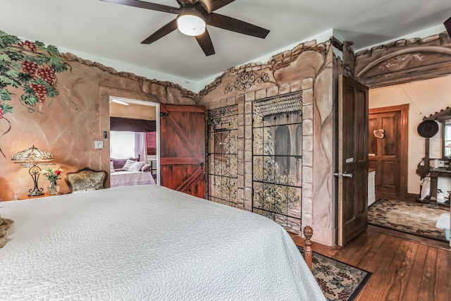 bedroom featuring hardwood / wood-style floors, ceiling fan, and a barn door