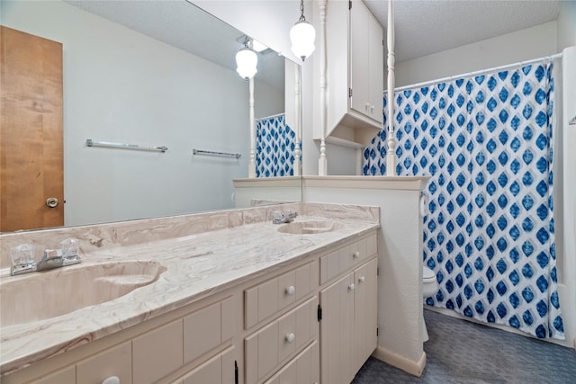 bathroom featuring a sink, a textured ceiling, toilet, and double vanity