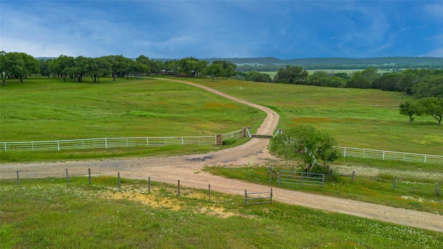 view of community with a rural view and fence