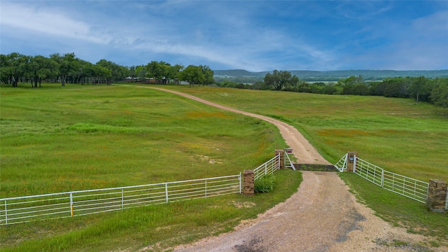 view of community with a rural view and fence