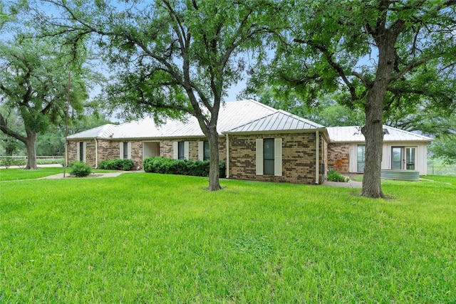 ranch-style house featuring brick siding, metal roof, and a front lawn