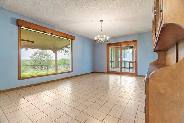 unfurnished room with ceiling fan with notable chandelier, a textured ceiling, baseboards, and light tile patterned floors