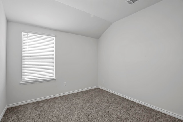 carpeted spare room featuring vaulted ceiling