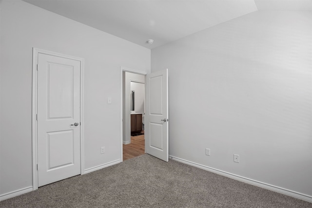 unfurnished bedroom featuring lofted ceiling and carpet floors