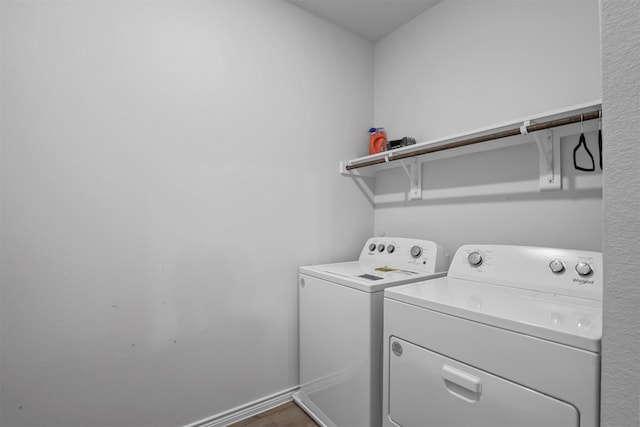 clothes washing area with hardwood / wood-style flooring and washer and clothes dryer