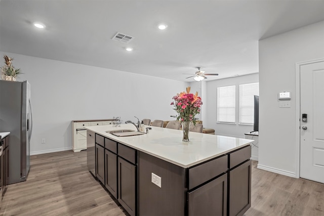 kitchen featuring light wood-type flooring, an island with sink, ceiling fan, and sink