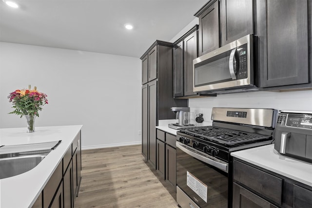 kitchen with light hardwood / wood-style flooring, stainless steel appliances, sink, and dark brown cabinets