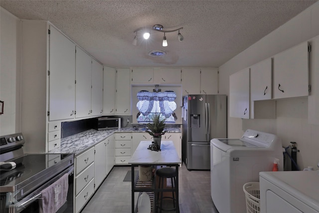 kitchen featuring independent washer and dryer, a textured ceiling, stainless steel appliances, and white cabinetry