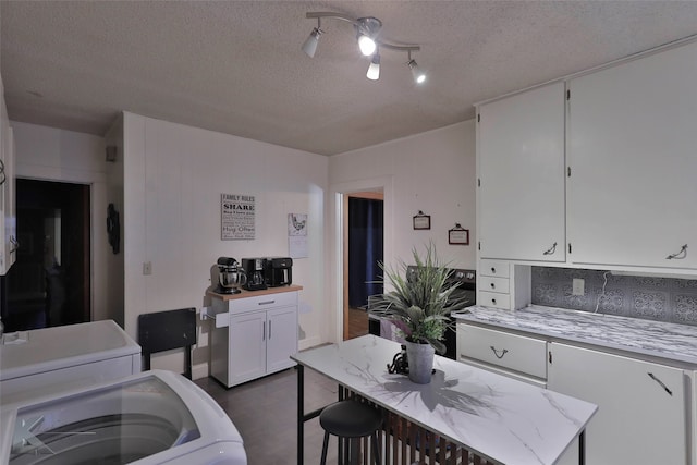 kitchen featuring a center island, light stone counters, white cabinetry, and a textured ceiling