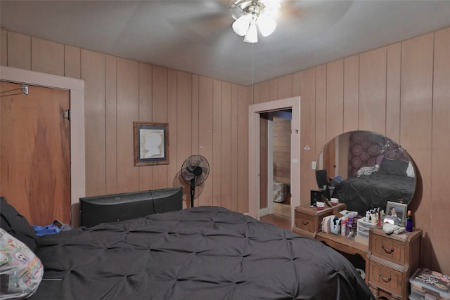 bedroom with ceiling fan, a closet, and wood walls