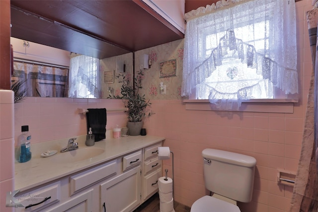 bathroom with vanity, toilet, and tile walls