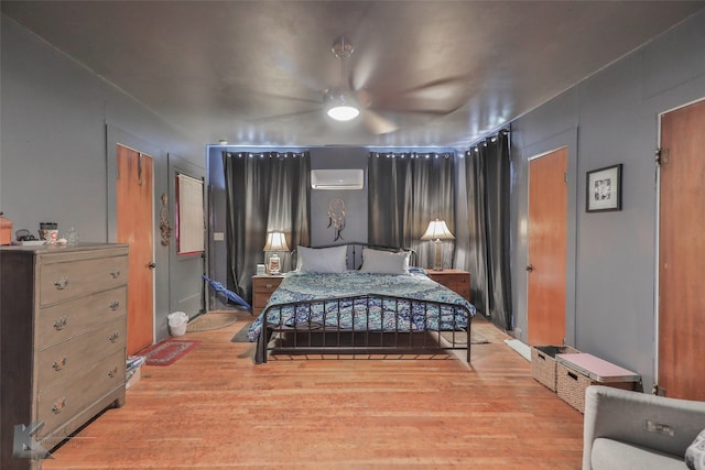 bedroom featuring ceiling fan, wood-type flooring, and a wall mounted air conditioner