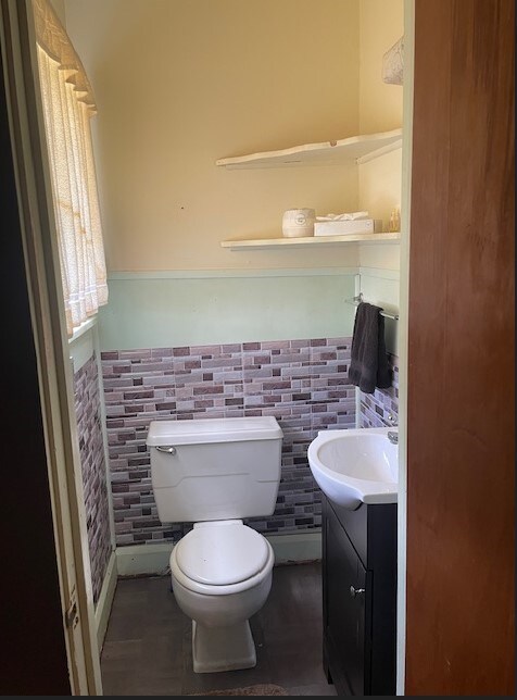 bathroom featuring vanity, toilet, and tile walls