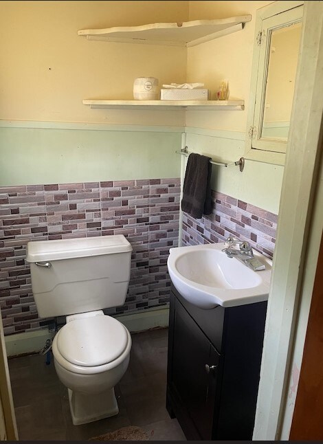 bathroom with vanity, tile walls, and toilet