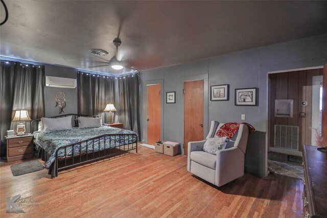 bedroom with a wall mounted air conditioner and hardwood / wood-style floors