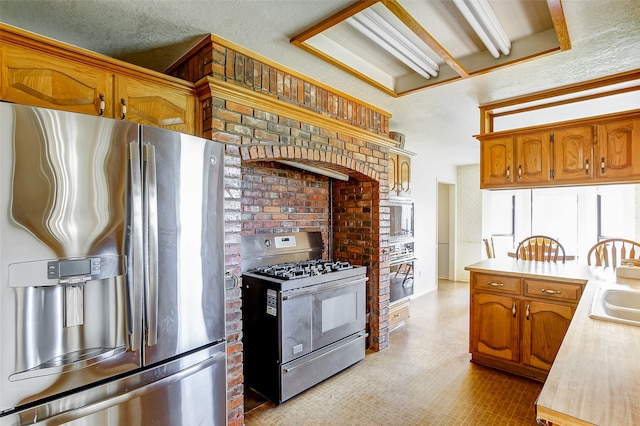 kitchen featuring stainless steel fridge, a wood stove, brick wall, sink, and gas range