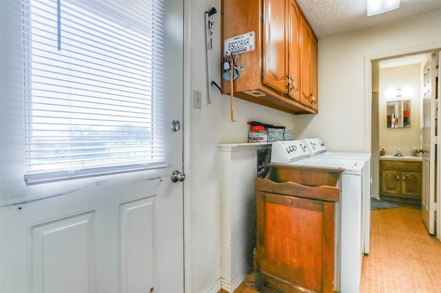 clothes washing area with washer and dryer, cabinets, sink, and a textured ceiling