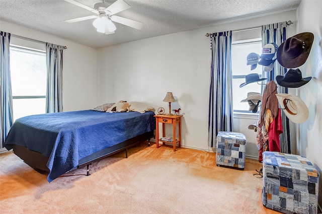 carpeted bedroom featuring ceiling fan, multiple windows, and a textured ceiling