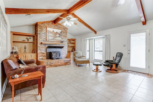 living room with a textured ceiling, a fireplace, vaulted ceiling with beams, ceiling fan, and light tile floors