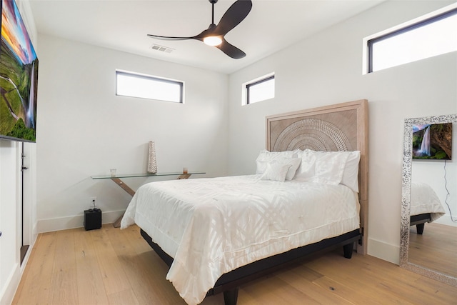 bedroom with ceiling fan, light hardwood / wood-style floors, and multiple windows