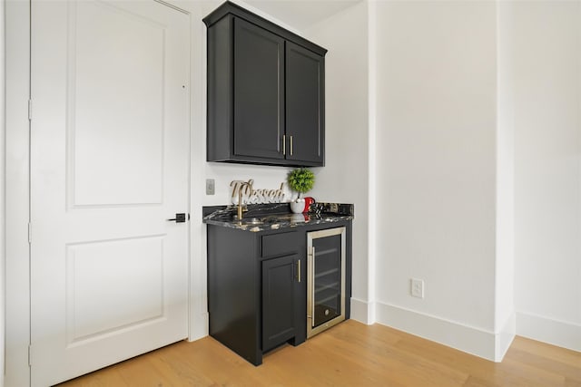 bar with wine cooler and light hardwood / wood-style flooring