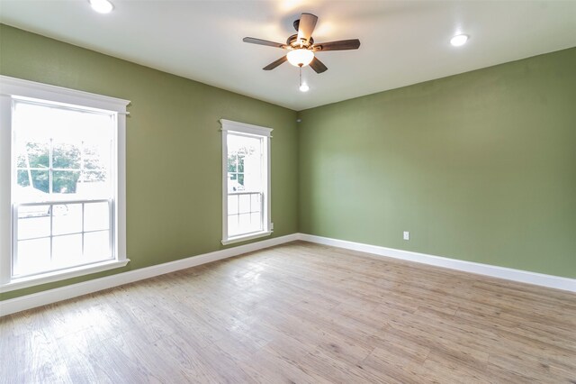 empty room with wood-type flooring, ceiling fan, and a healthy amount of sunlight