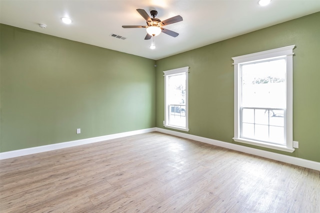 unfurnished room featuring a wealth of natural light, ceiling fan, and light wood-type flooring