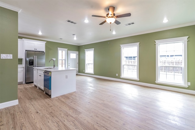 kitchen featuring a healthy amount of sunlight, appliances with stainless steel finishes, light wood-type flooring, and an island with sink