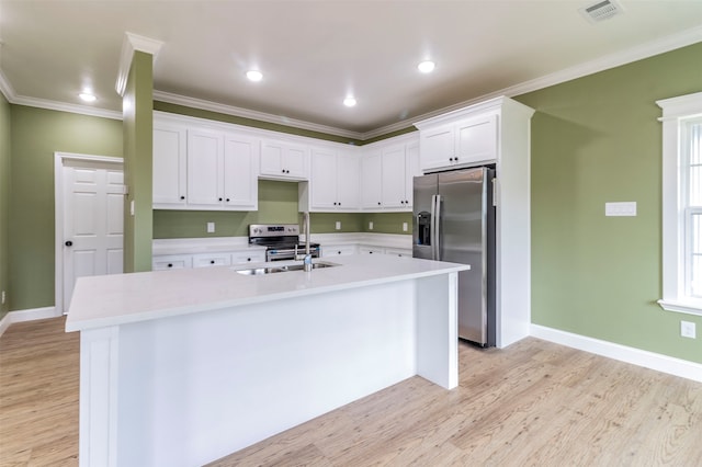 kitchen with a kitchen island with sink, crown molding, white cabinetry, appliances with stainless steel finishes, and light hardwood / wood-style floors