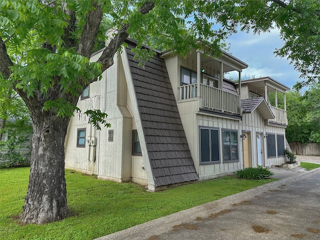 view of side of property with a balcony and a yard