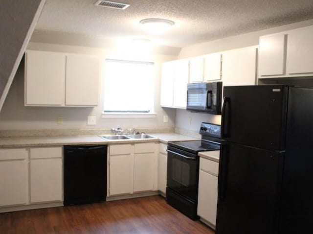 kitchen featuring sink, white cabinetry, black appliances, and dark wood-type flooring